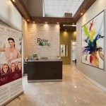 Doctor's office reception area interior design - https://www.andyquinones.net Httpswww Andyquinones Net modern reception area with a dark wood front desk stone accent wall reading rejuv chip and large colorful abstract artwork on the right wall