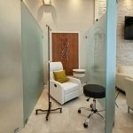 Doctor's office interior design - https://www.andyquinones.net Httpswww Andyquinones Net waiting area in a modern clinic with white armchair yellow cushion and small round tables enclosed by frosted glass partitions